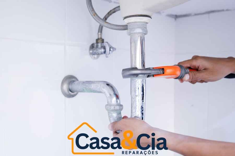 canalizador apertando conexões de encanamento embaixo da pia com chave de tubo