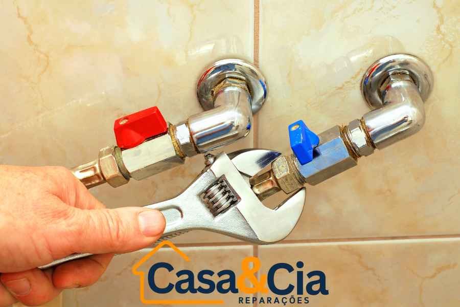 Canalizador ajustando válvulas de água com chave inglesa, garantindo vedação e funcionamento correto.